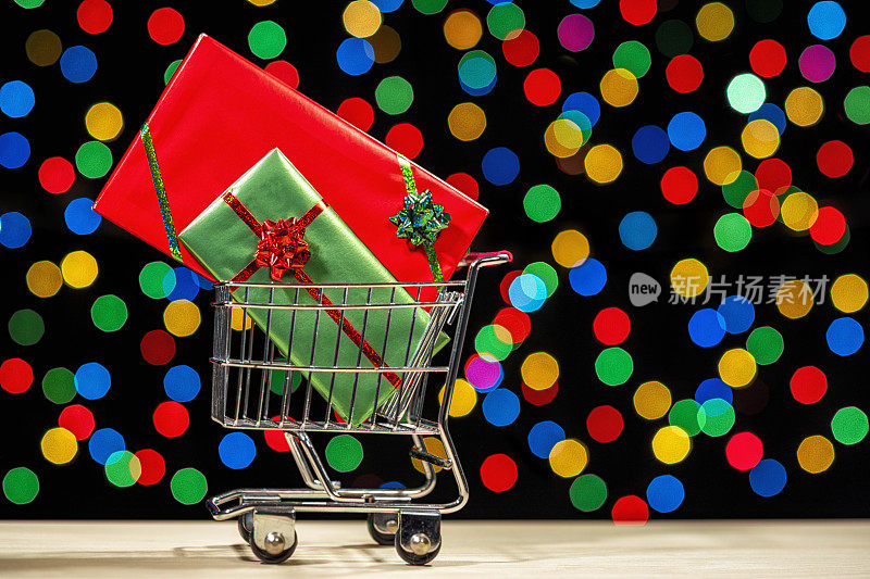 Shopping cart full of wrapped big screen TVs against multi-colored bokeh – Concept online shopping
